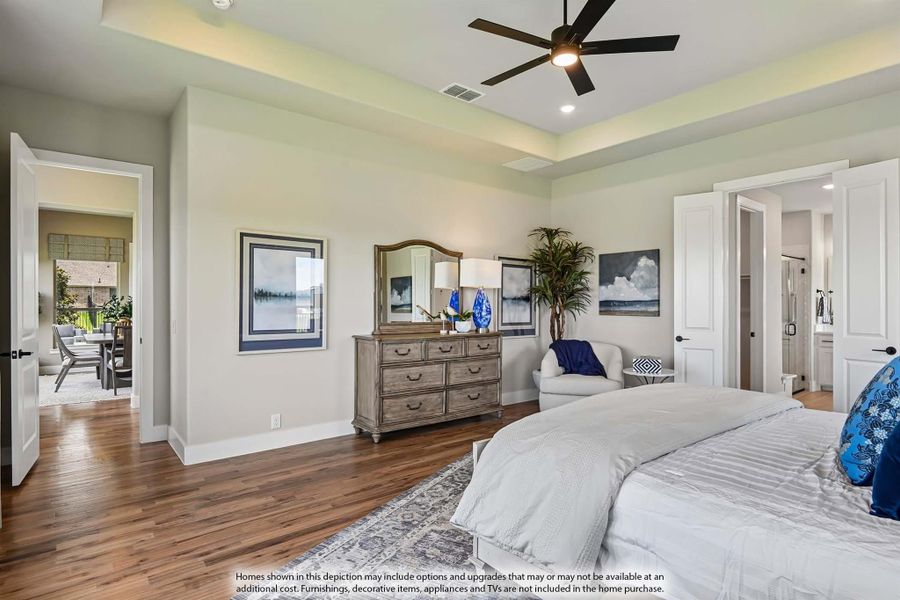 Master bedroom with tray ceiling, ceiling fan, hardwood floors, and wood dresser with mirror Master bedroom with tray ceiling, ceiling fan, hardwood floors, and wood dresser with mirror