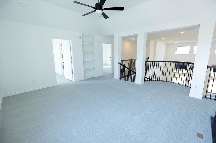 Carpeted spare room featuring ceiling fan and built in features