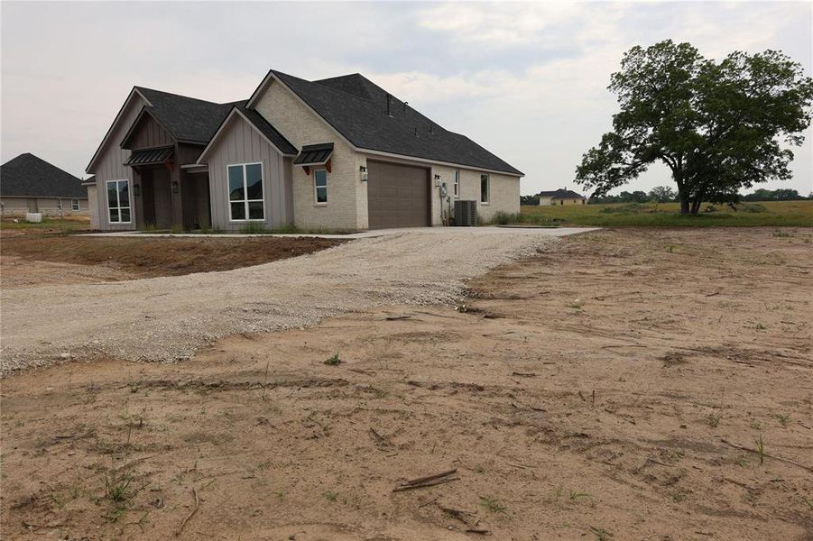 View of front of home with a garage and central AC