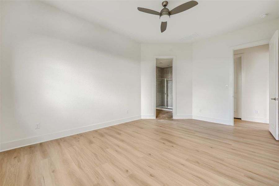 Unfurnished bedroom featuring light wood-style flooring, ceiling fan, and a walk in closet