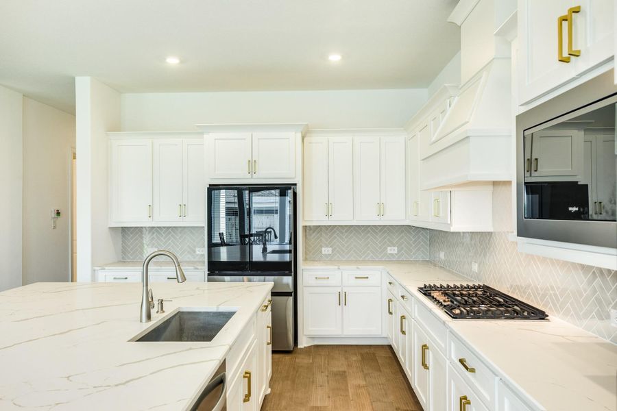 Stunning kitchen features including a farmhouse stainless steel sink, designer-grade hardware, and a beautifully curated tile backsplash.
