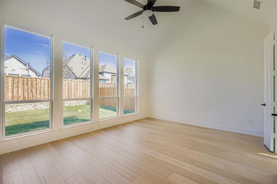 Unfurnished sunroom featuring wood finished floors, high vaulted ceiling, and a residential view Unfurnished sunroom featuring wood finished floors, high vaulted ceiling, and a residential view