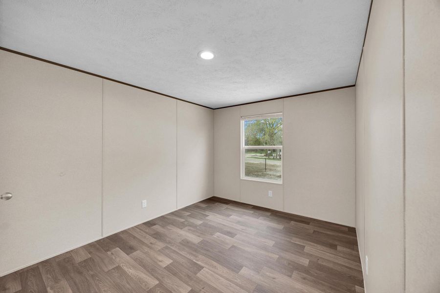 Spare room featuring light wood-style floors, a textured ceiling, and ornamental molding
