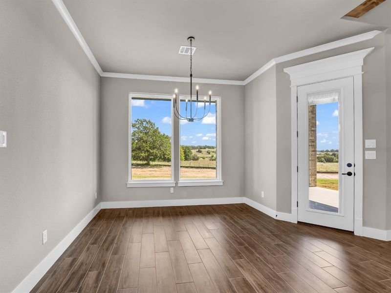 Unfurnished dining area featuring a chandelier, dark wood-style floors, and crown molding