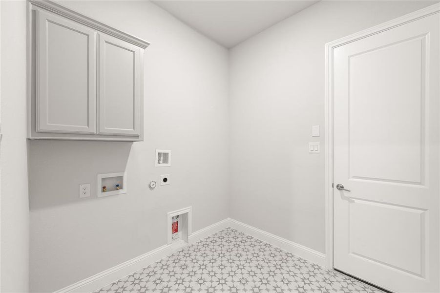 Laundry room with hookup for an electric dryer, cabinet space, gas dryer hookup, light floors, and baseboards