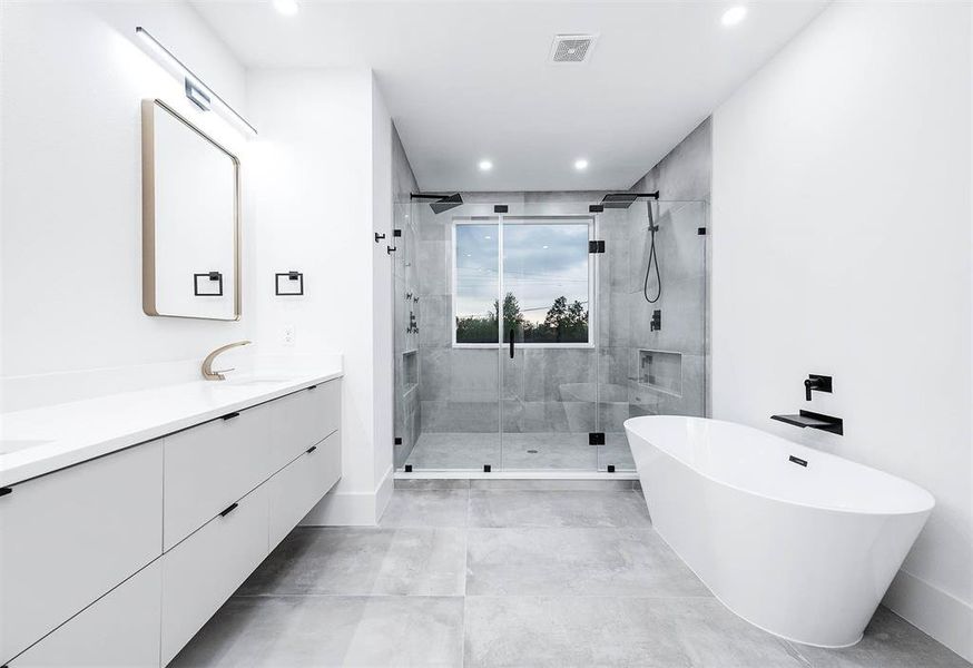 This is a modern bathroom featuring a sleek double vanity, a large walk-in shower with glass enclosure, and a freestanding bathtub. It has clean lines, minimalist design elements, and a neutral color palette.