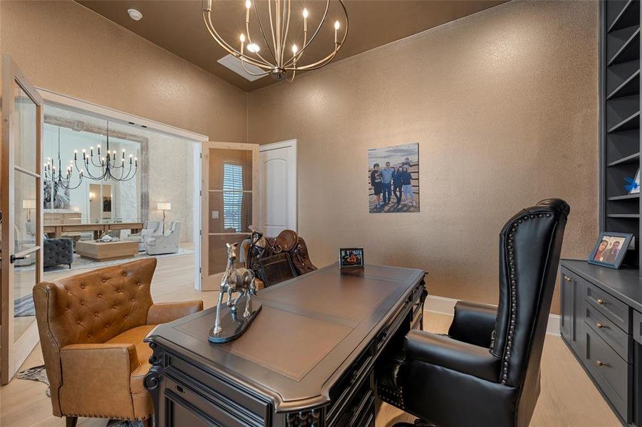 Office with a chandelier, a textured wall, and light wood-type flooring