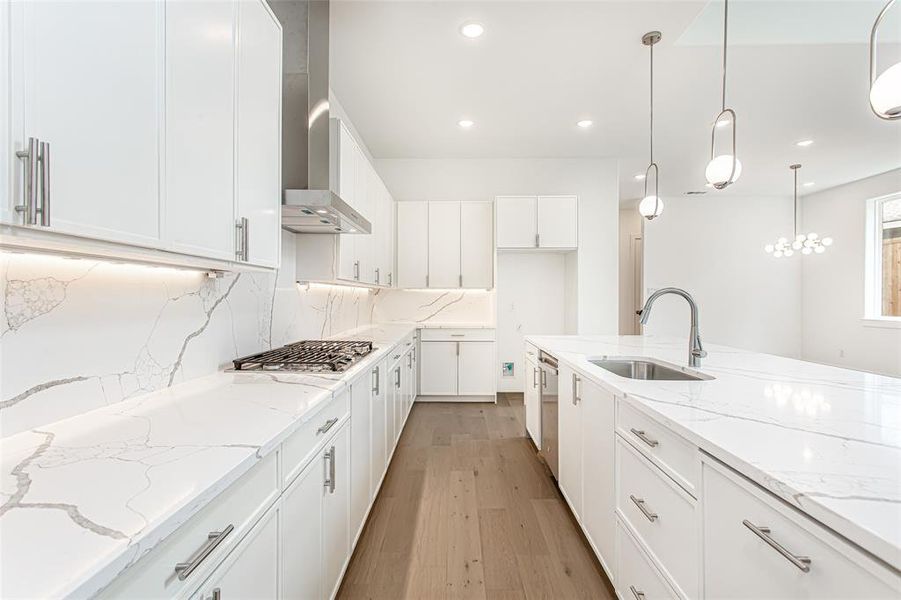 Kitchen featuring a sink, stainless steel appliances, wall chimney range hood, recessed lighting, and white cabinetry