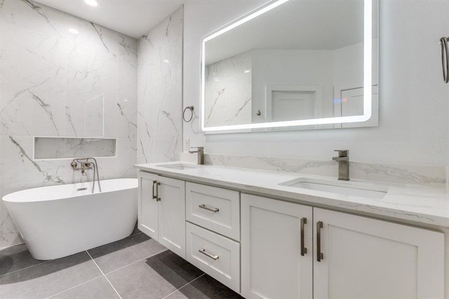 Bathroom with a bathtub, vanity, and tile patterned floors