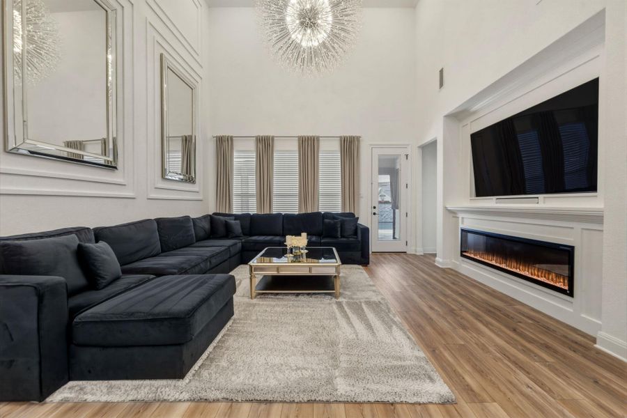 Living area featuring high ceilings, a contemporary linear fireplace, and decorative wall molding