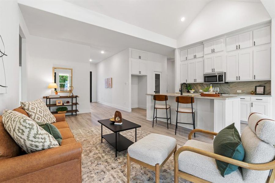 Living room featuring sink, light hardwood / wood-style floors, and high vaulted ceiling