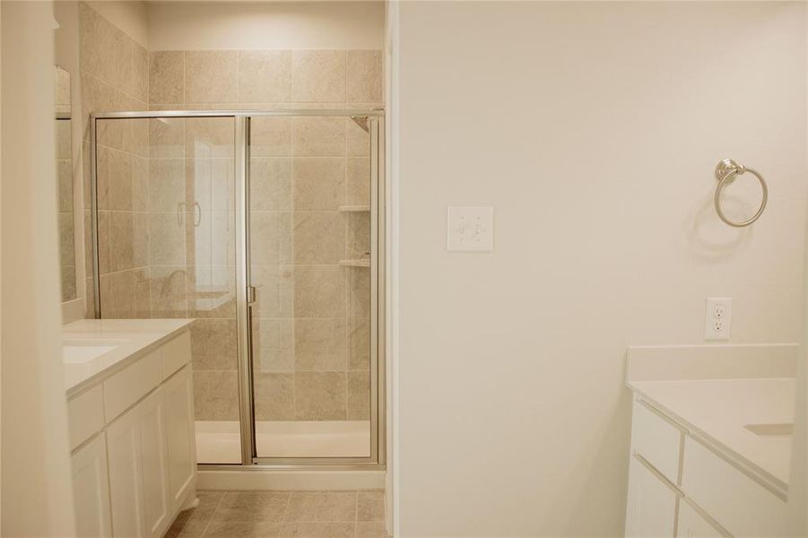 Bathroom featuring tile patterned flooring, vanity, and an enclosed shower