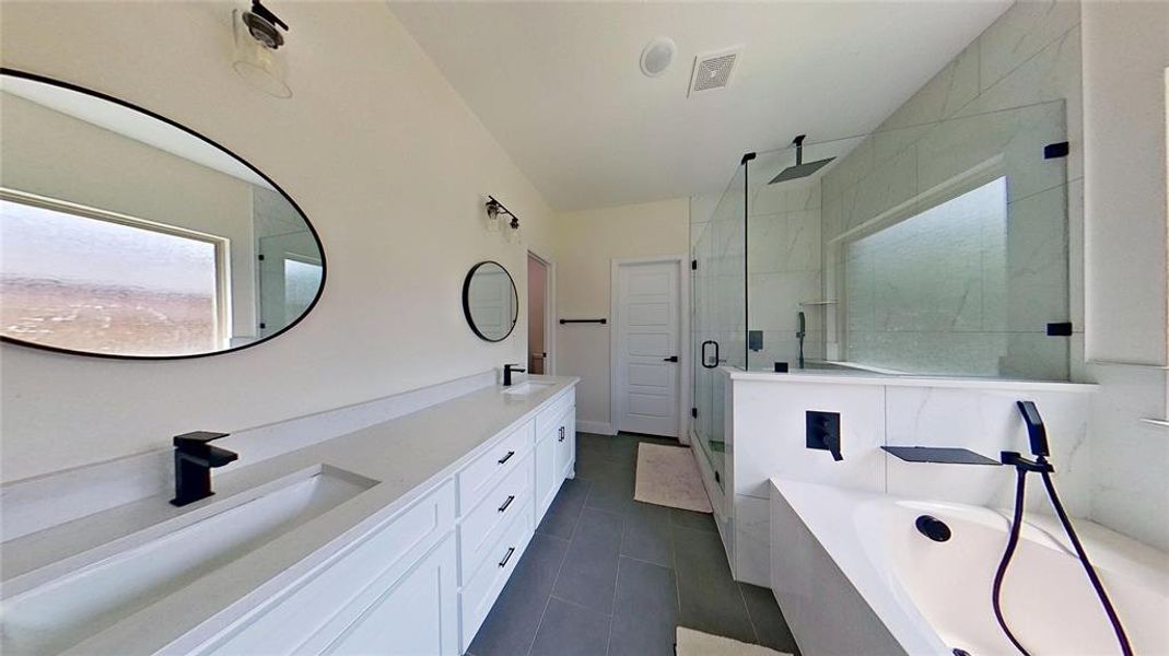Bathroom with a shower stall, a garden tub, double vanity, and dark tile patterned flooring