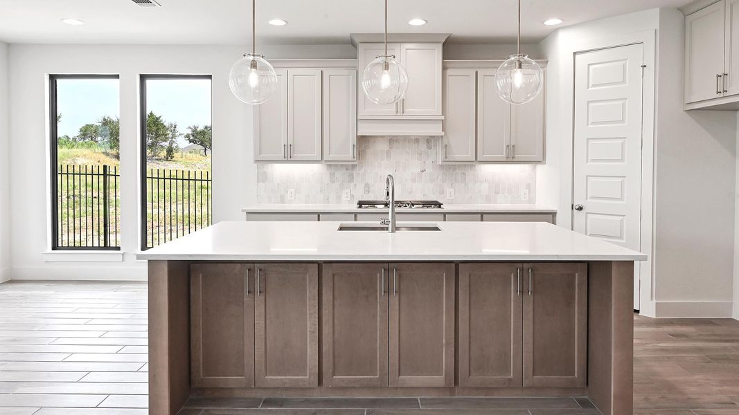 Kitchen with light countertops, wood finished floors, recessed lighting, plenty of natural light, and a center island with sink Kitchen with light countertops, wood finished floors, recessed lighting, plenty of natural light, and a center island with sink