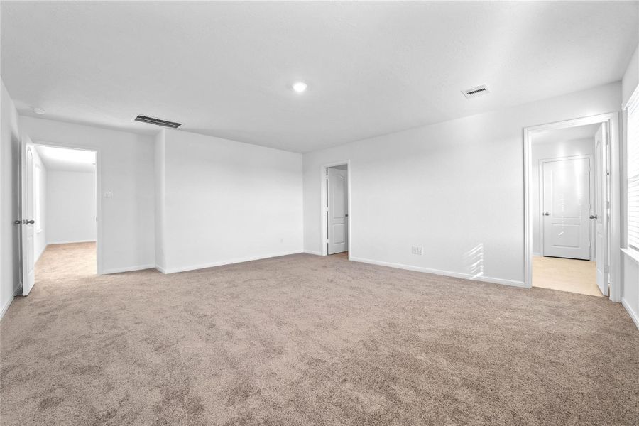 Additional view of the primary bedroom looking to the ensuite primary bathroom and walk-in closet. Additional view of the primary bedroom looking to the ensuite primary bathroom and walk-in closet.