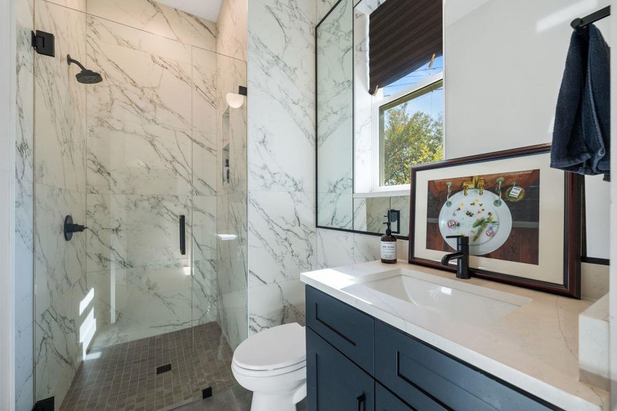Bathroom featuring vanity and a marble finish shower