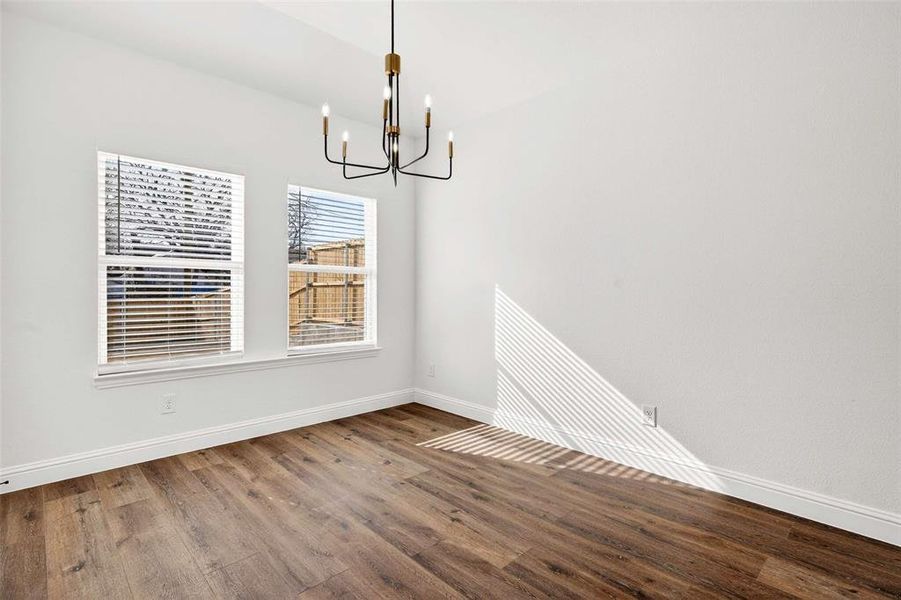 Unfurnished dining area featuring wood finished floors and a chandelier