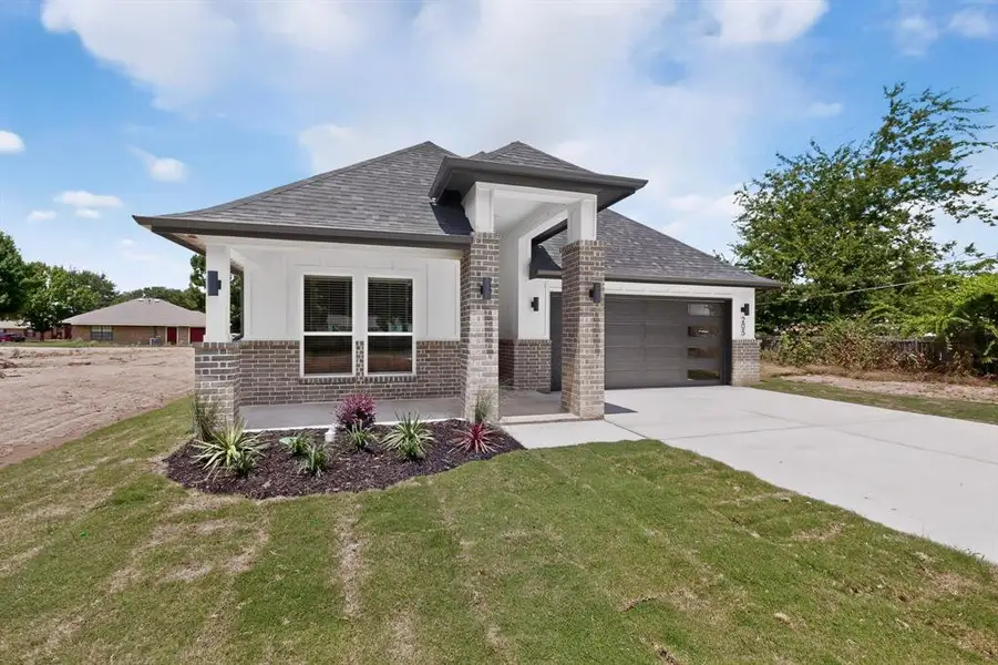 Modern exterior featuring brick and white siding accents, a dark gray shingled roof, and a contemporary garage door with frosted glass panels