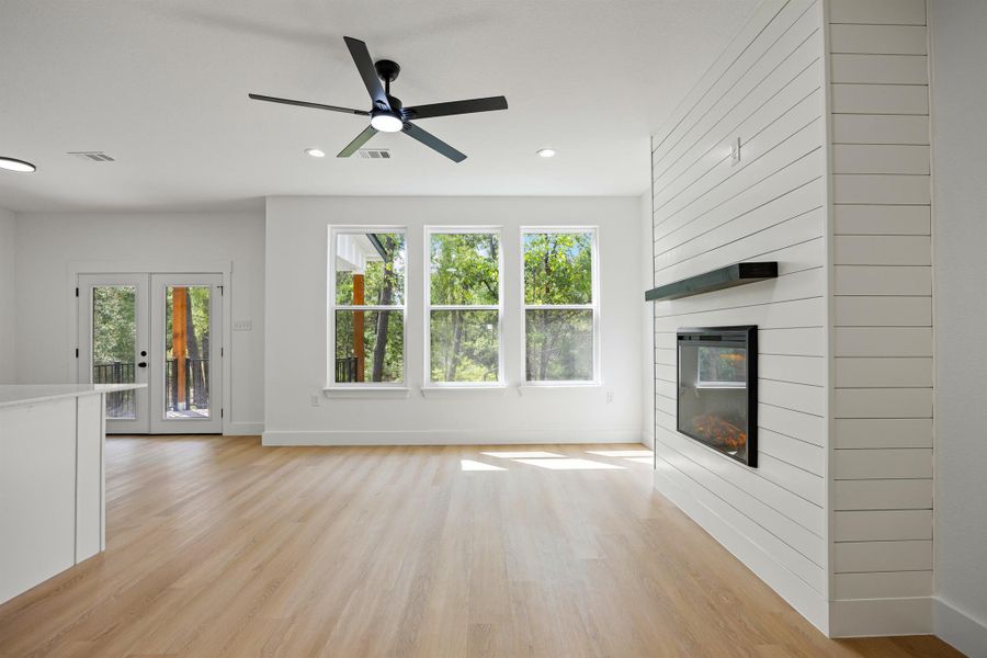 Unfurnished living room featuring light wood-type flooring, a fireplace, recessed lighting, and a ceiling fan Unfurnished living room featuring light wood-type flooring, a fireplace, recessed lighting, and a ceiling fan