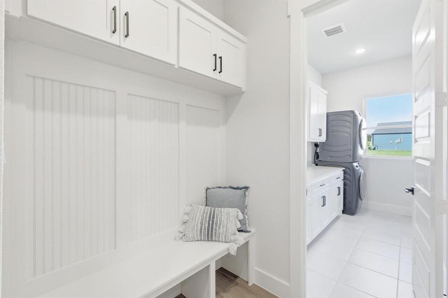 Mud room with custom built-in cabinets, closet and direct access to laundry room