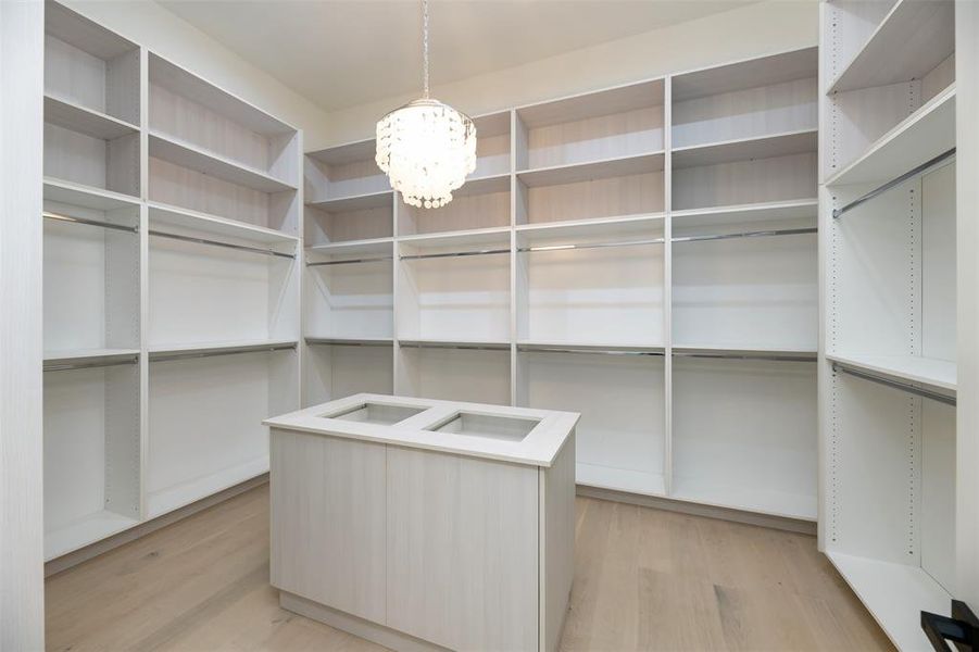 Spacious closet featuring light wood-style flooring and a chandelier