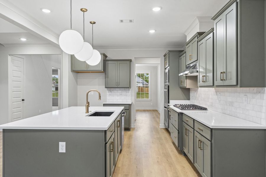 Contemporary kitchen featuring a large island with white countertop, brass-tone faucet, and undermount sink Contemporary kitchen featuring a large island with white countertop, brass-tone faucet, and undermount sink