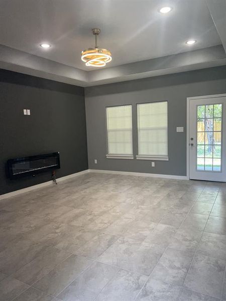 Unfurnished living room with a raised ceiling, recessed lighting, and decorative-heating fireplace. Unfurnished living room with a raised ceiling, recessed lighting, and decorative-heating fireplace.