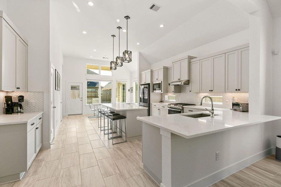 A chef's dream! This super-sized kitchen boasts abundant cabinetry for storage, a generous island, a practical breakfast bar, and stylish pendant lighting. A chef's dream! This super-sized kitchen boasts abundant cabinetry for storage, a generous island, a practical breakfast bar, and stylish pendant lighting.