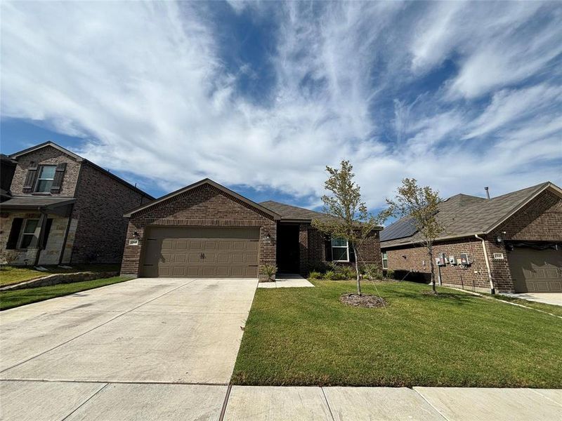 View of front of house with a garage, a front lawn, concrete driveway, and brick siding