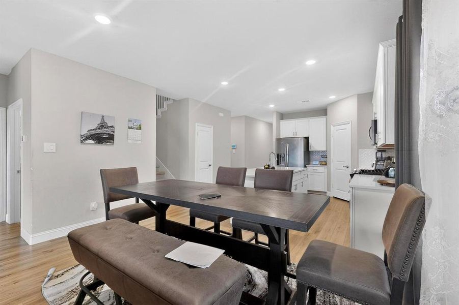 Dining area featuring light wood-style flooring, recessed lighting, and stairs Dining area featuring light wood-style flooring, recessed lighting, and stairs