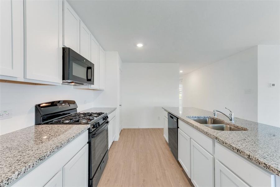 Kitchen with white cabinets, light hardwood / wood-style floors, sink, and black appliances