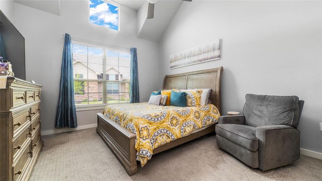 Carpeted bedroom with a towering ceiling and ceiling fan