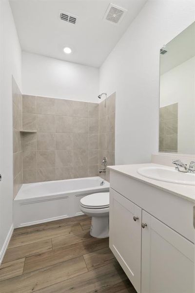 Full bathroom with tiled shower / bath, toilet, and vanity with extensive cabinet space
