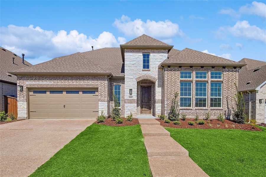 View of front of property featuring a front yard and a garage