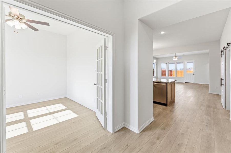 Corridor with a barn door, recessed lighting, and light wood-type flooring Corridor with a barn door, recessed lighting, and light wood-type flooring
