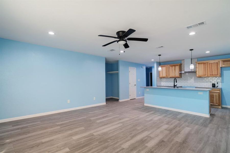 Kitchen featuring tasteful backsplash, an island with sink, light wood-style floors, open floor plan, and recessed lighting Kitchen featuring tasteful backsplash, an island with sink, light wood-style floors, open floor plan, and recessed lighting