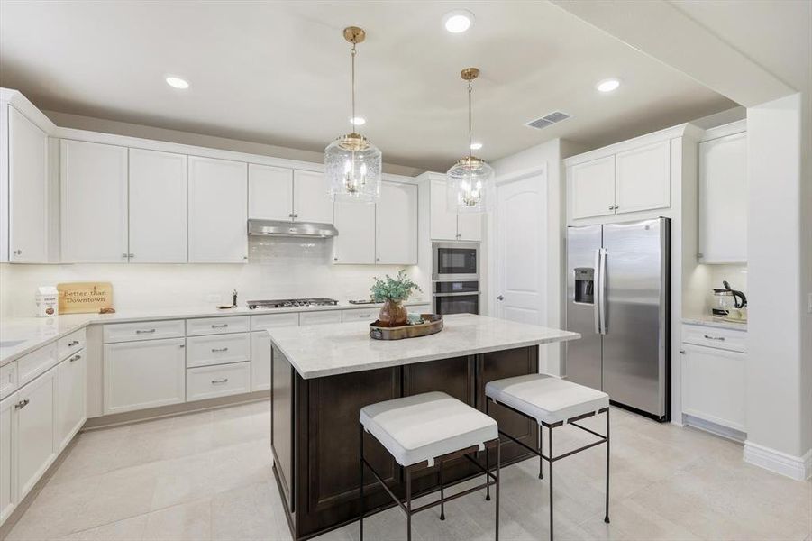Kitchen with stainless steel appliances, a breakfast bar area, recessed lighting, a kitchen island, and pendant lighting