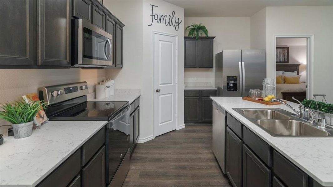 Kitchen featuring stainless steel appliances, light countertops, dark wood-style floors, and a kitchen island