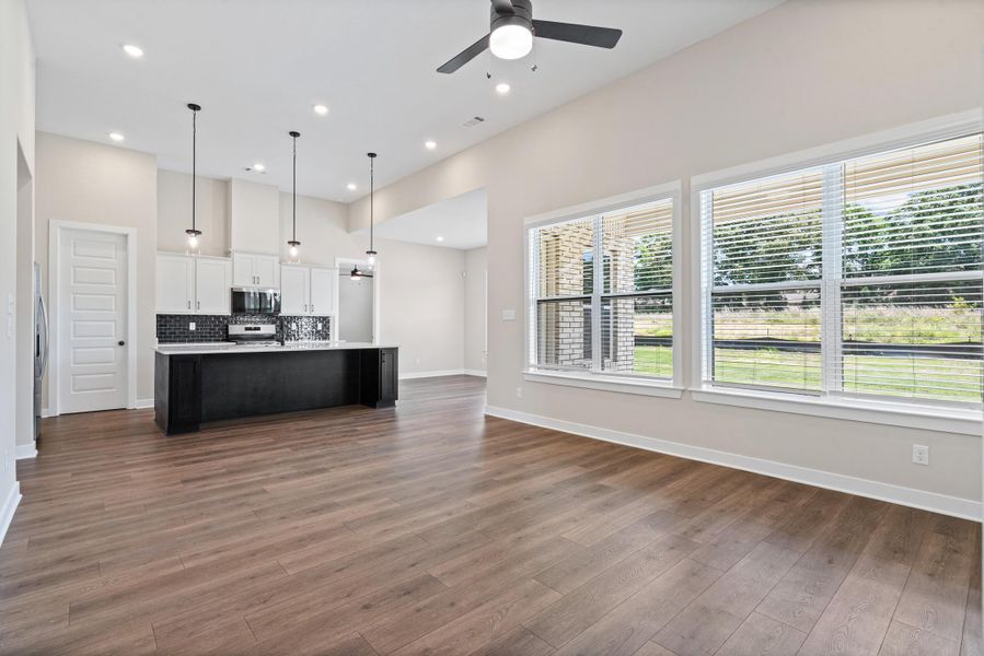 Open-concept living area with wood-finish flooring, vaulted ceilings, and recessed lighting Open-concept living area with wood-finish flooring, vaulted ceilings, and recessed lighting