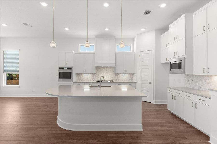 Kitchen with white cabinetry, dark wood finished floors, stainless steel appliances, hanging light fixtures, and decorative backsplash