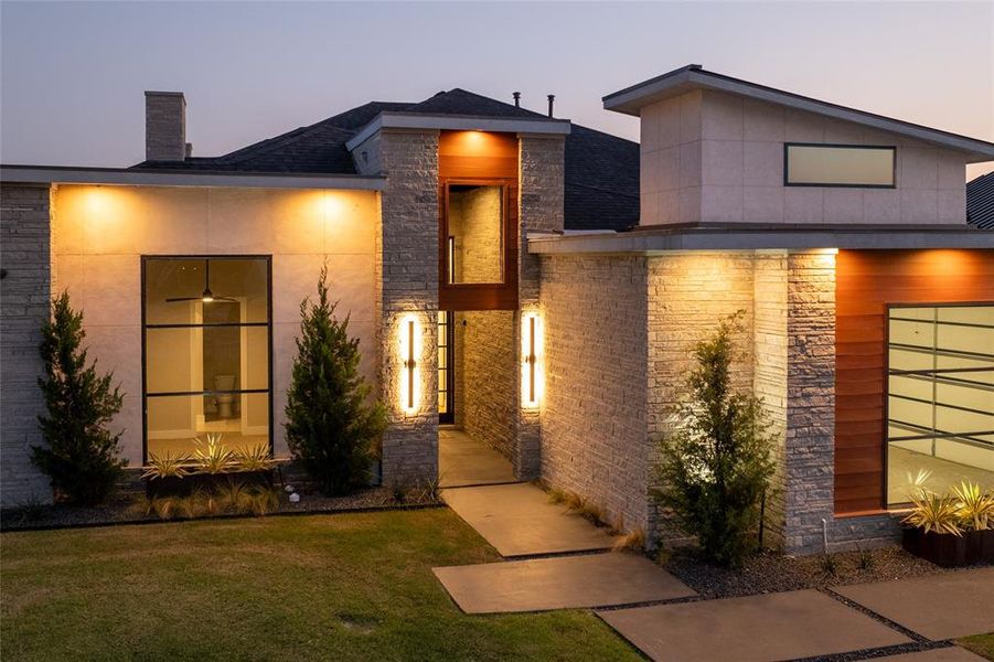 Exterior entry at dusk featuring a lawn