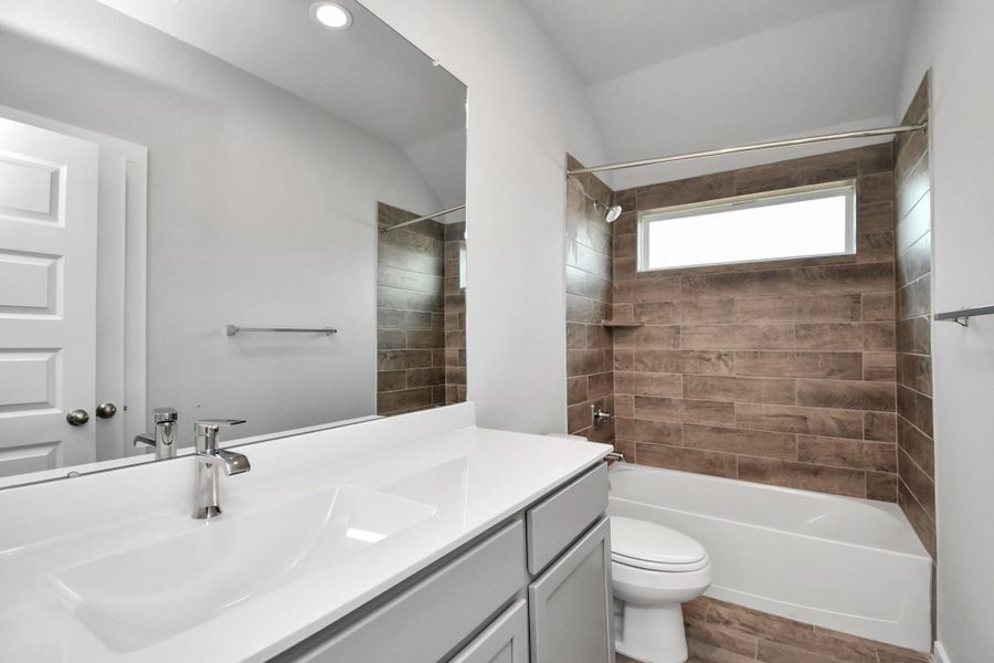 Secondary bath features tile flooring, bath/shower combo with tile surround, light stained wood cabinets, beautiful light countertop. Sample photo of completed home with similar floor plan. As-built interior colors and selections may vary. Secondary bath features tile flooring, bath/shower combo with tile surround, light stained wood cabinets, beautiful light countertop. Sample photo of completed home with similar floor plan. As-built interior colors and selections may vary.
