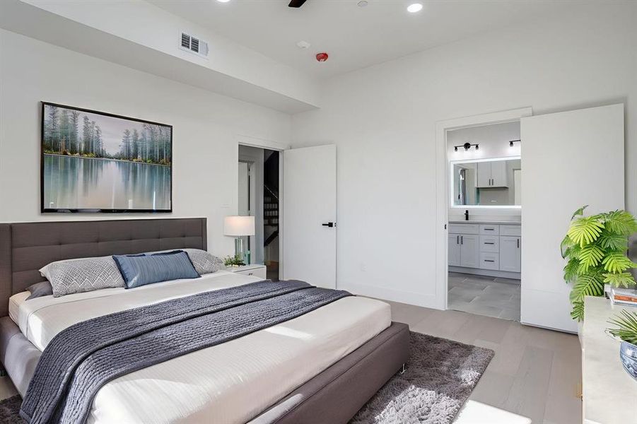 Bedroom with light wood finished floors, recessed lighting, and ensuite bathroom