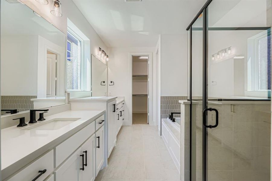 Full bath featuring a stall shower, two vanities, a garden tub, light tile patterned flooring, and a spacious closet