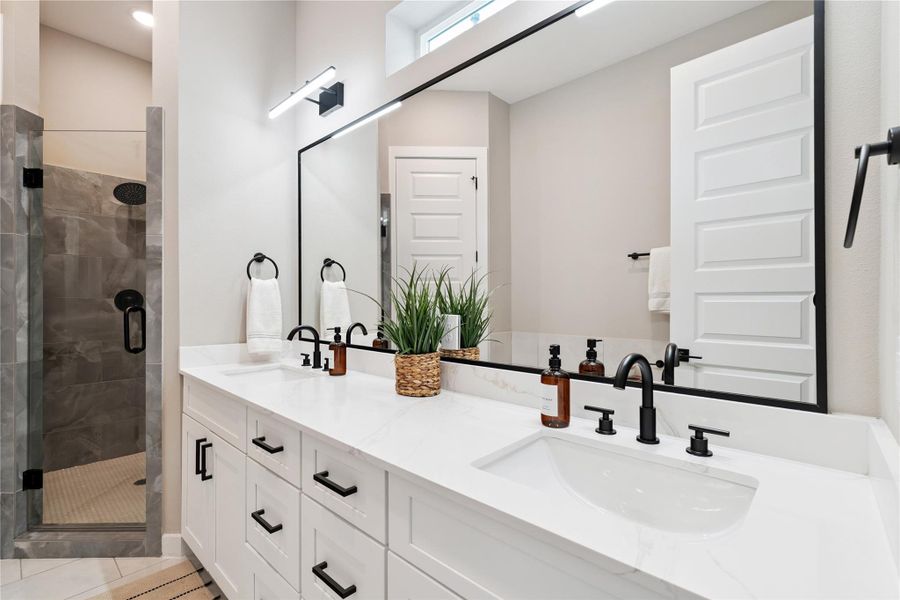 Architectural discipline defines this ensuite—matte black fixtures, warm light, and softened corners.