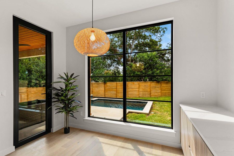 A large picture window frames views of the backyard pool area and lawn.