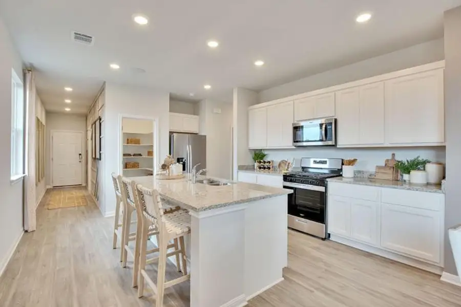 Kitchen featuring appliances with stainless steel finishes, a sink, light wood-style flooring, a kitchen island with sink, and recessed lighting