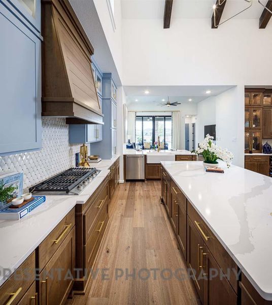 Kitchen featuring appliances with stainless steel finishes, light wood finished floors, beamed ceiling, decorative backsplash, and glass insert cabinets Kitchen featuring appliances with stainless steel finishes, light wood finished floors, beamed ceiling, decorative backsplash, and glass insert cabinets