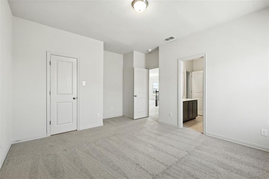 Unfurnished bedroom featuring light colored carpet and ensuite bathroom Unfurnished bedroom featuring light colored carpet and ensuite bathroom