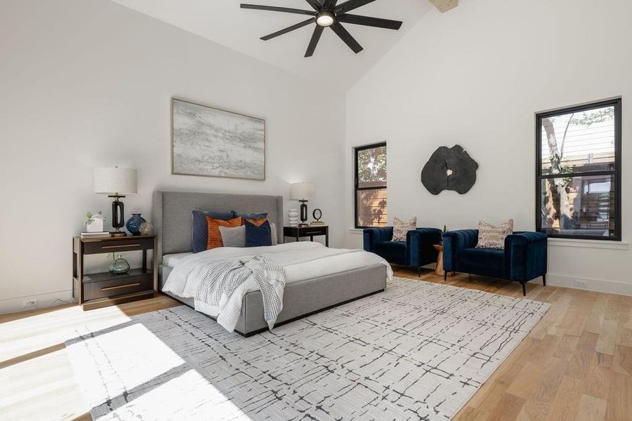 Bedroom with ceiling fan, high vaulted ceiling with beam, and light hardwood flooring